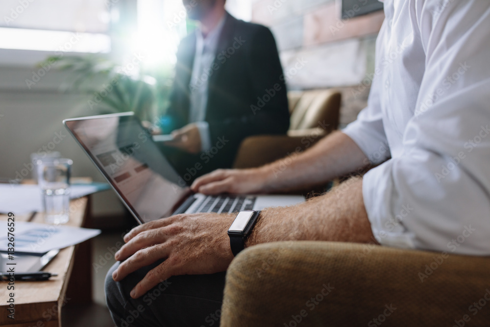 Businessman working on laptop during corporate meeting