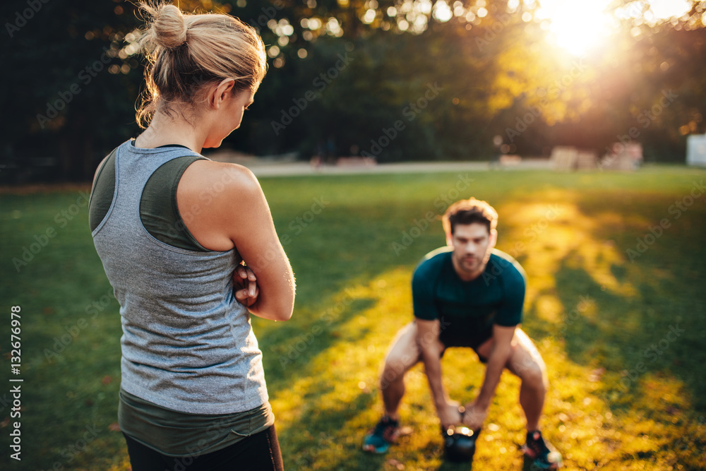 Female trainer in the park with man working out