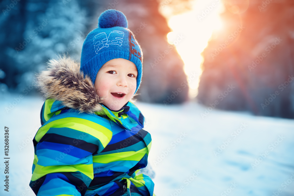 Boy in knitted hat, gloves and scarf outdoors at snowfall