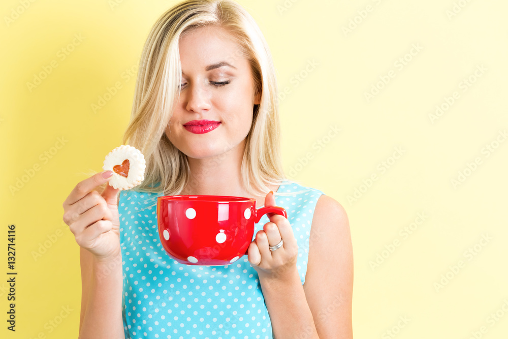 Happy young woman with cookie and coffee