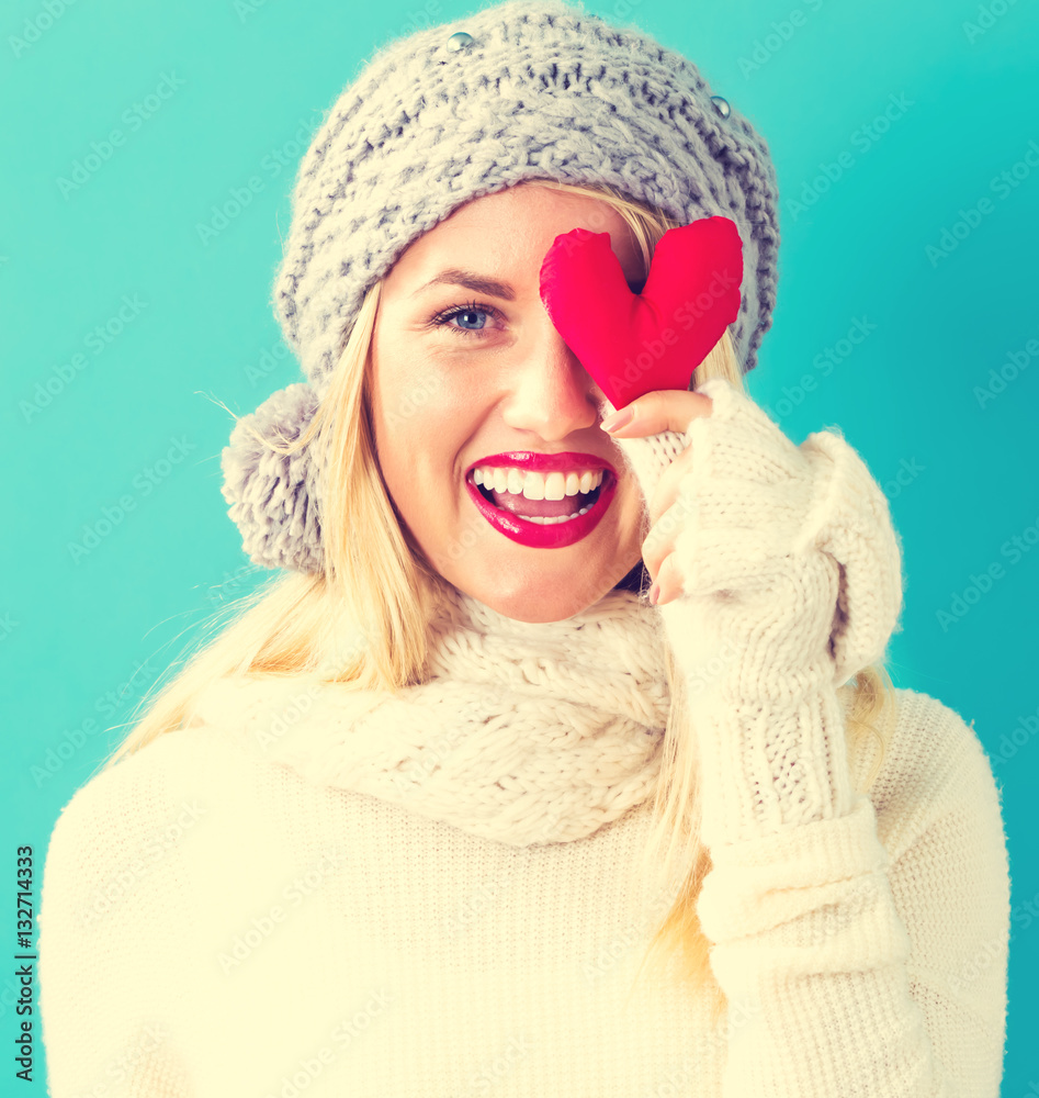 Happy young woman holding a heart cushion