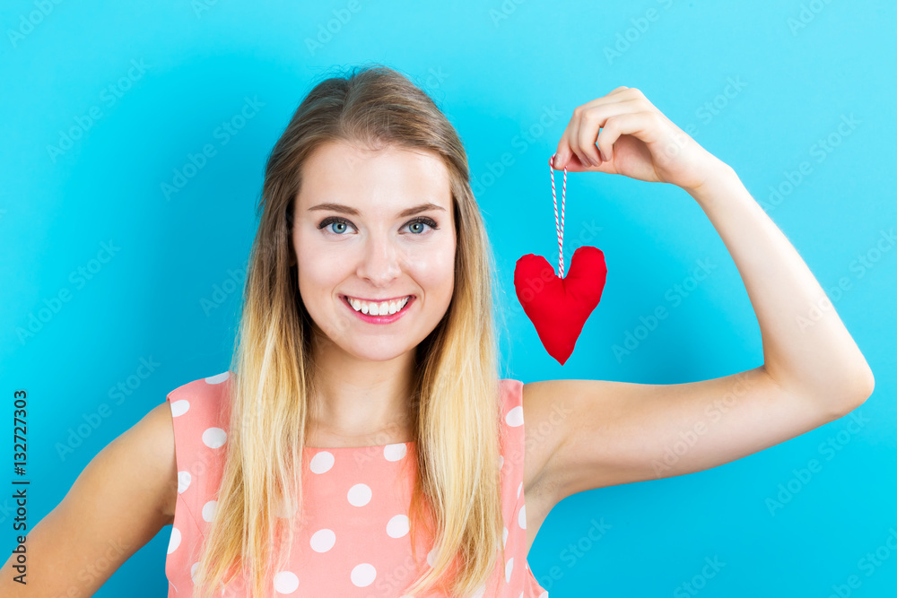 Happy young woman holding a heart cushion