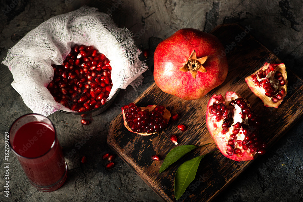 Pomegranate fruits with grains and leaves on the table. Make juice. Top view. Dark moody.