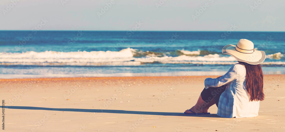 Woman in a hat sitting on the beach