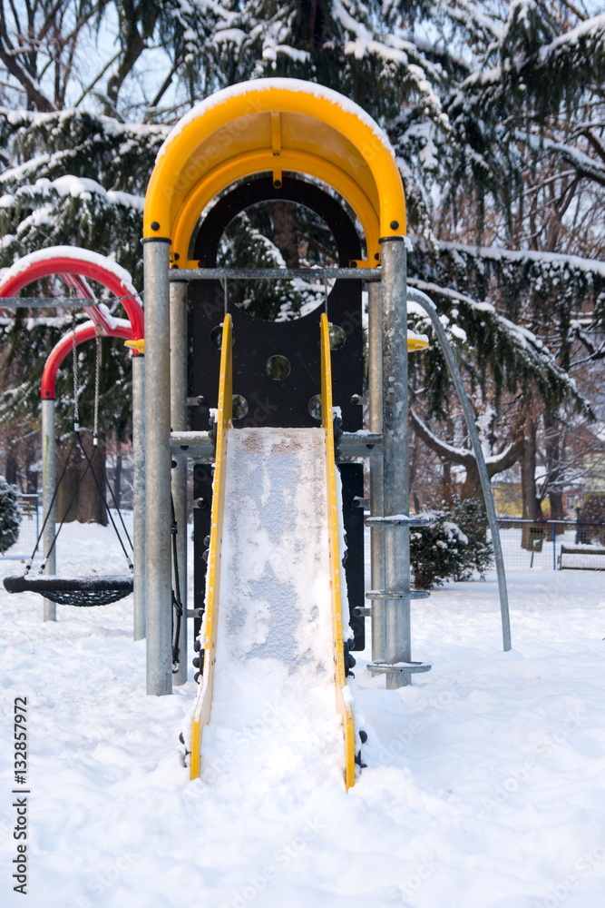 Empty slide in snow covered park