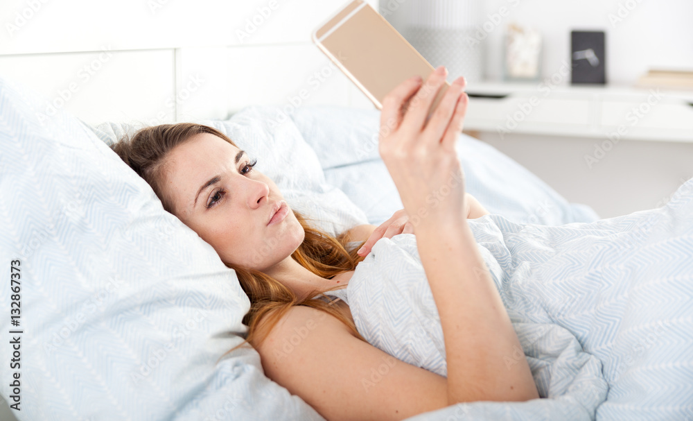 Young girl taking selfie photo in bed after waking up