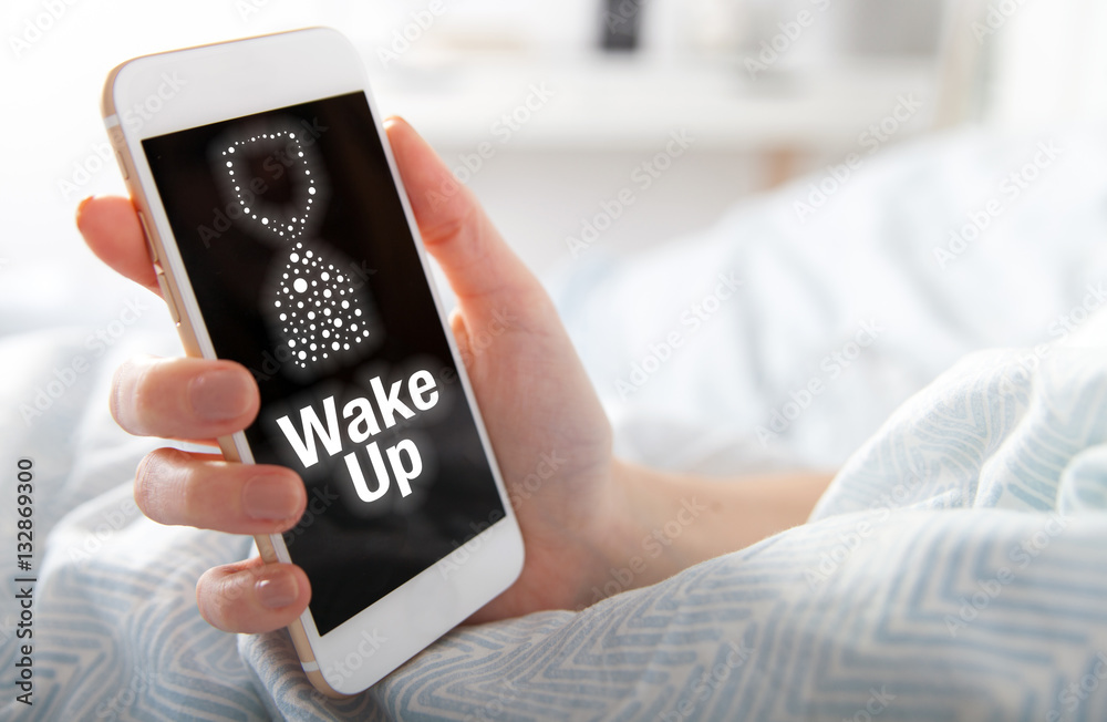 Wake Up on smart phone screen, girl lying in bed