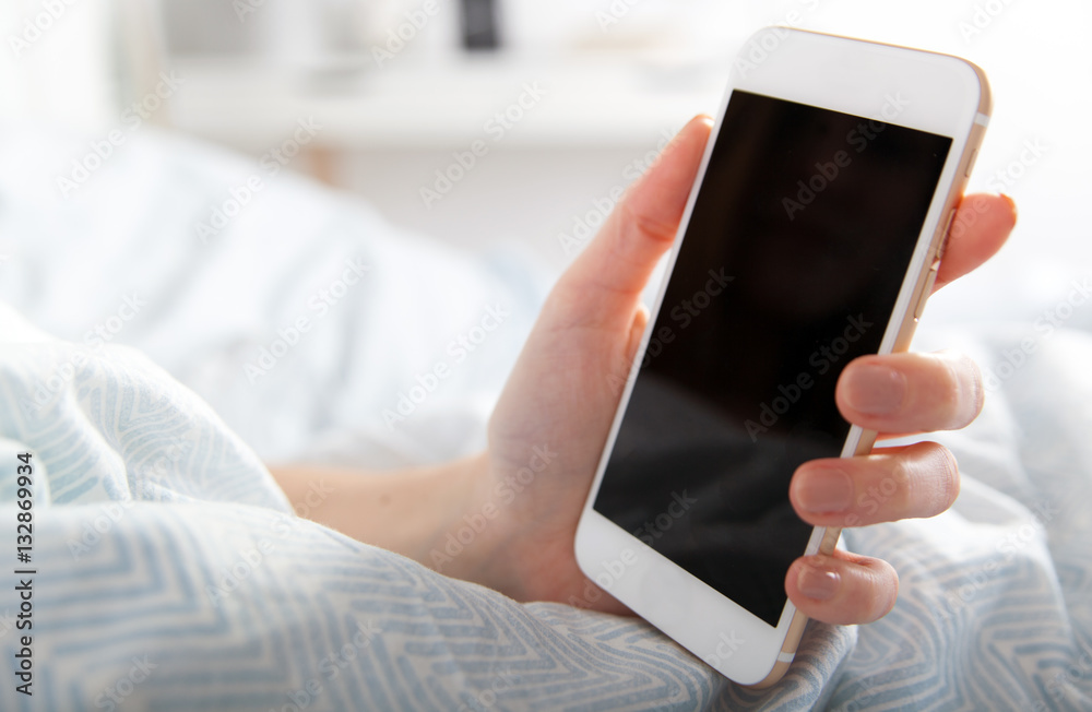 Morning in bed Woman holding smartphone, close up blank screen