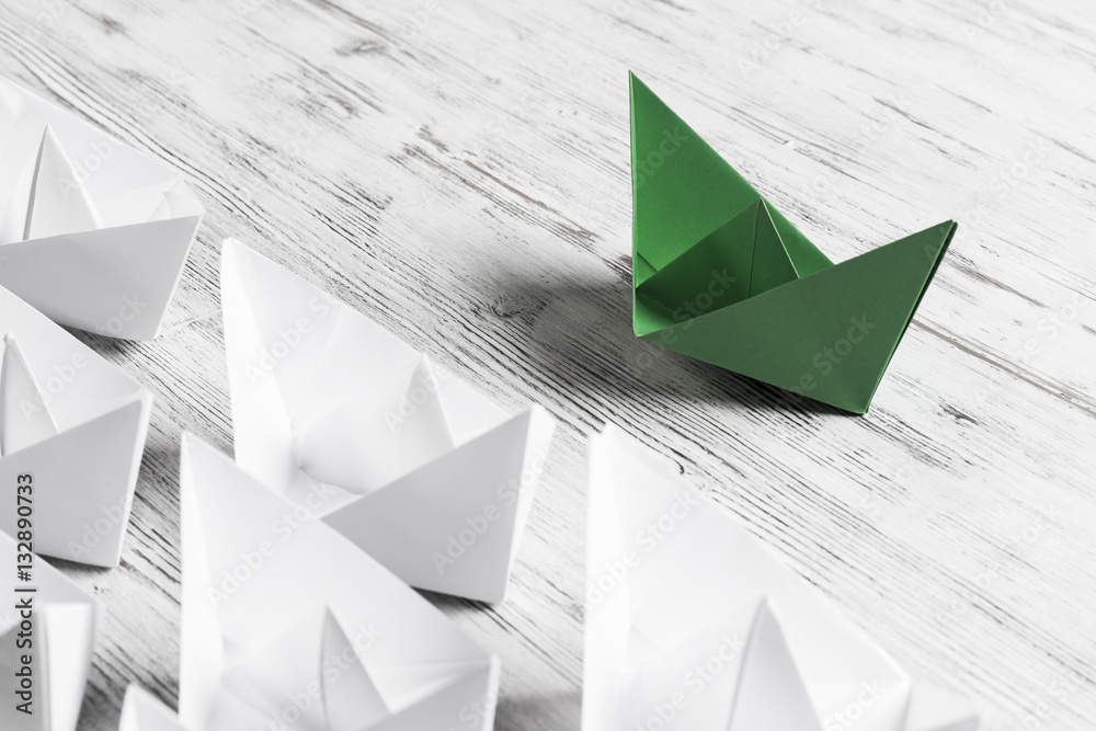 Business leadership concept with white and color paper boats on 