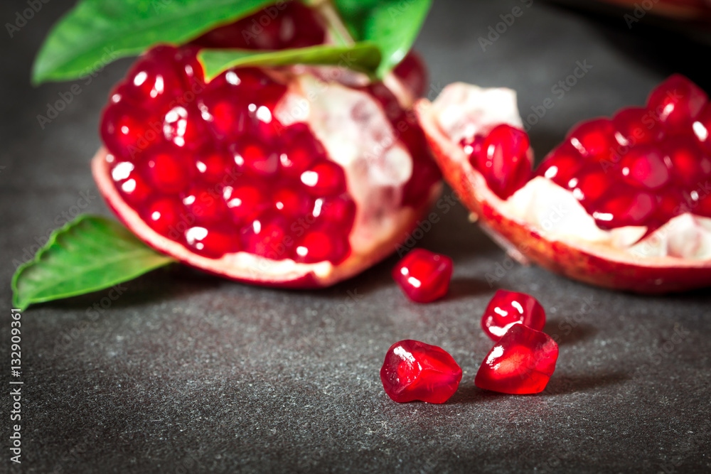 Fresh red pomegranate  seed  with leaves over black stone 