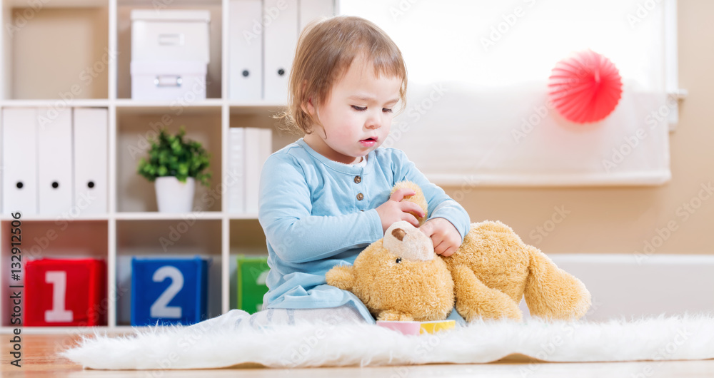 Toddler girl have tea with her teddy bear