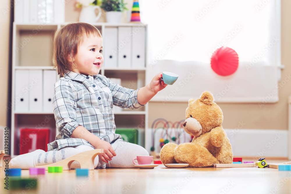 Happy toddler girl playing with her teddy bear