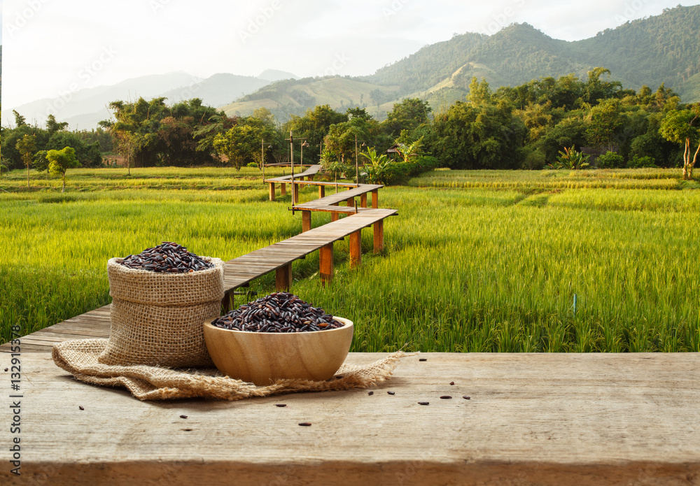 Rice berry in bowl and burlap sack on wooden table with the rice