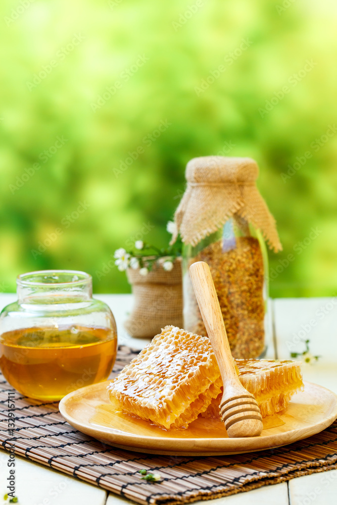 Honeycomb with jar and bee pollen on white wooden background