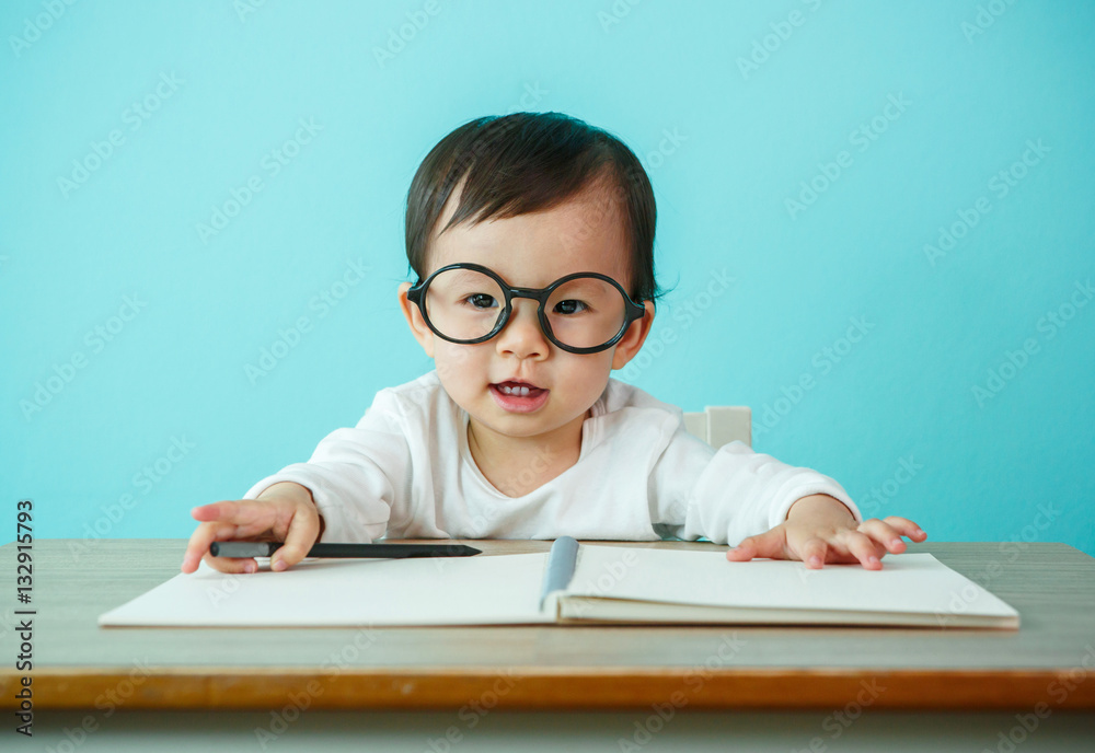 Asian baby girl smiling wearing glasses, on the table (soft focu