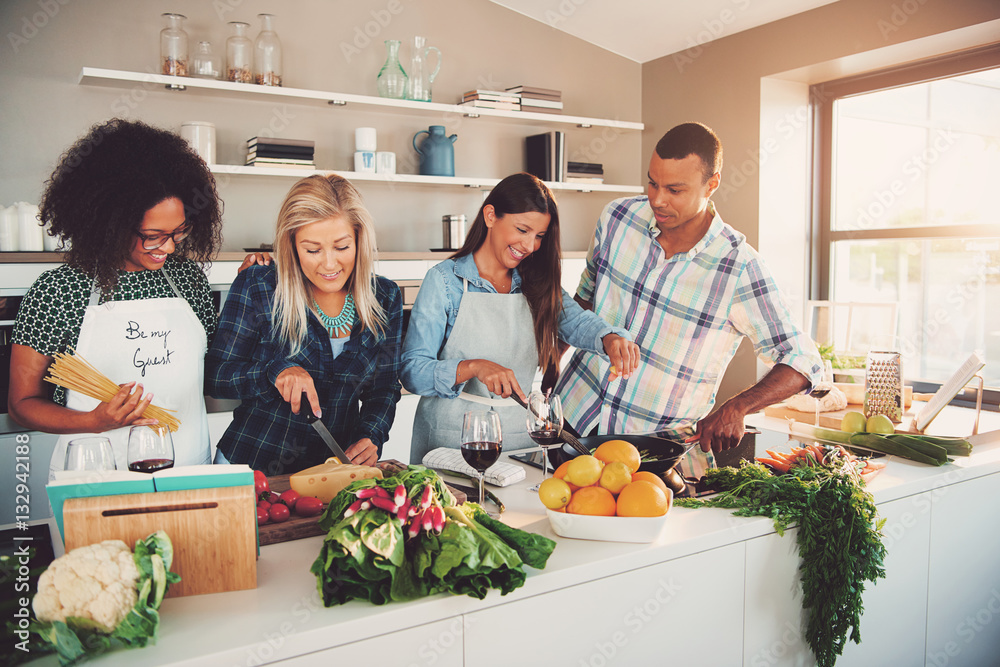 Four mixed friends preparing a meal in kitchen