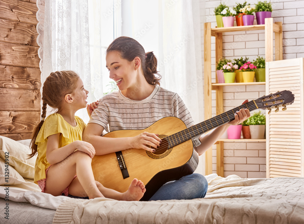 woman playing guitar for child girl