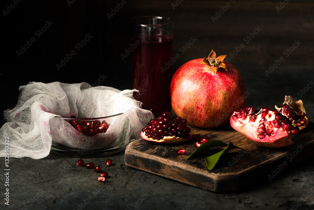 Pomegranate fruits with grains and leaves on the table. Make juice. Dark moody.