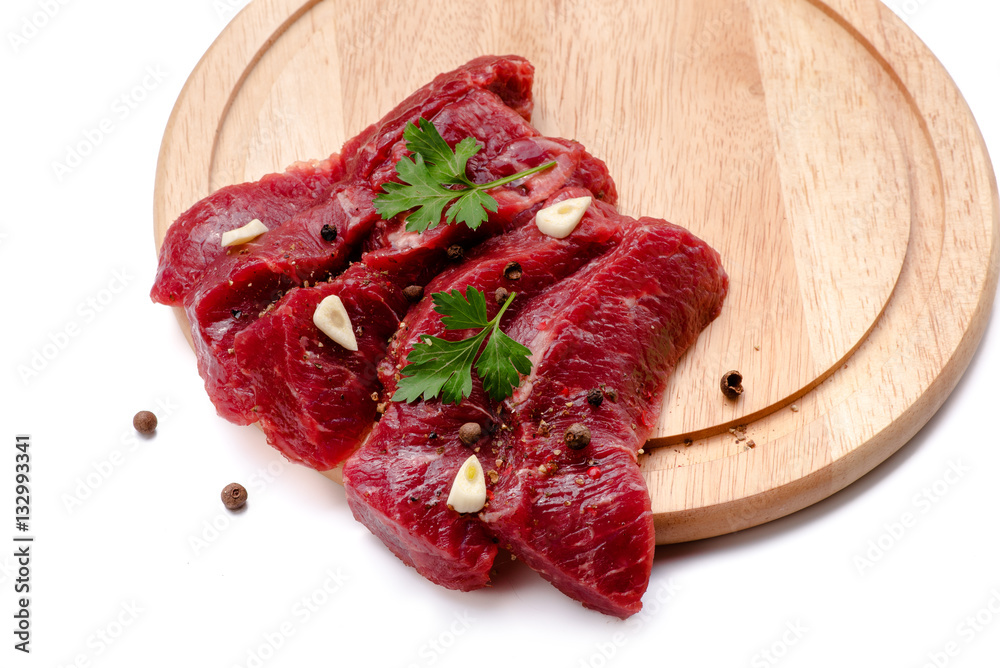 Pieces of meat with garlic and parsley on wooden board isolated. Raw beef. Top view.