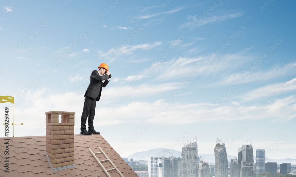 Engineer man standing on roof and looking in binoculars. Mixed media