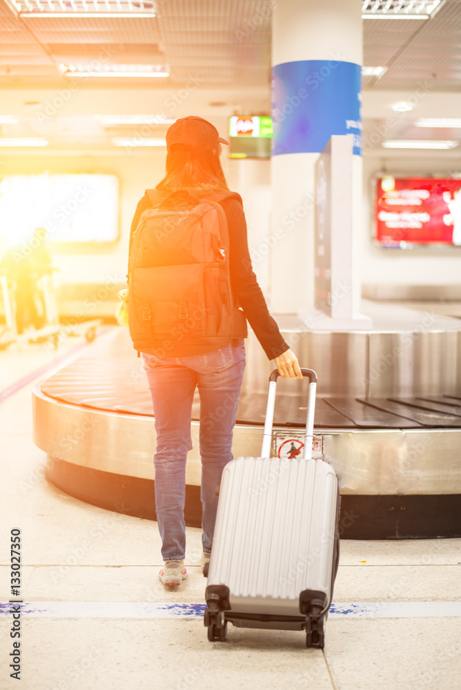 Traveler women waiting bag in the mpty baggage claim area at airport