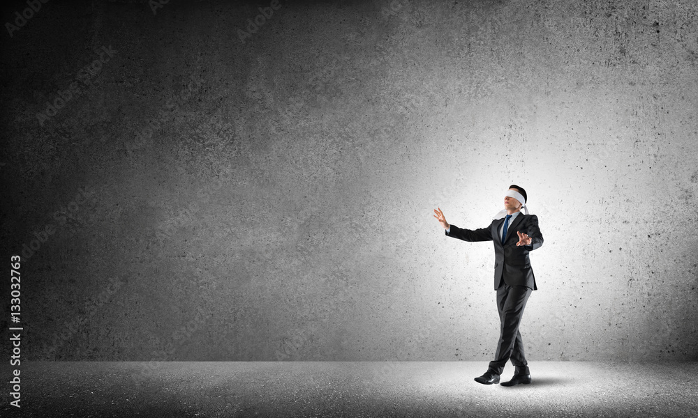 Business concept of risk with businessman wearing blindfold in empty concrete room