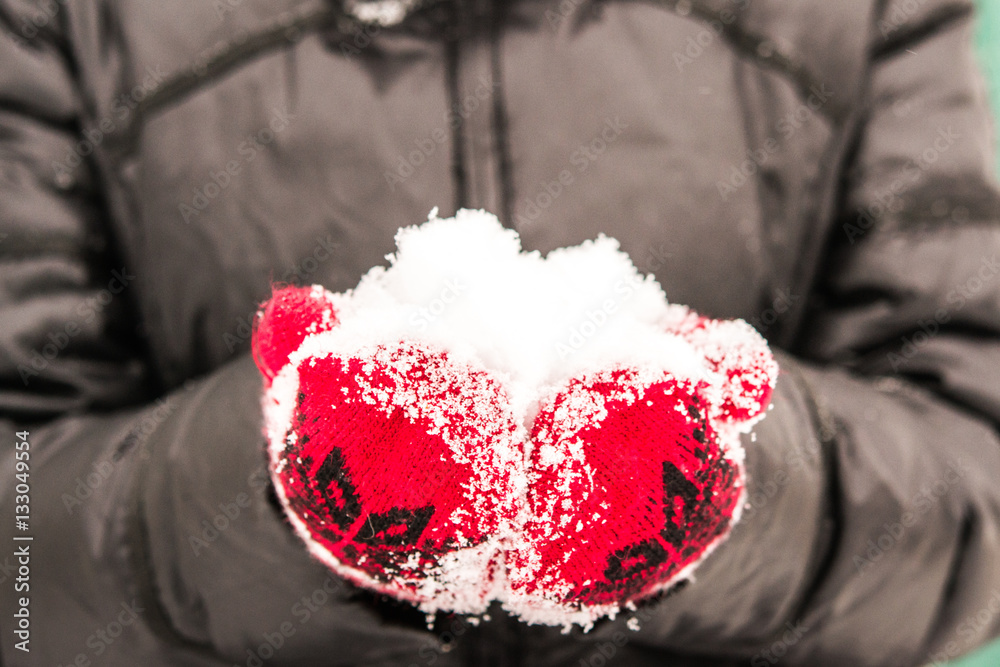 girl in red mitten holding a handful of snow close-up. Beautiful snowy cold winter conceptual image 