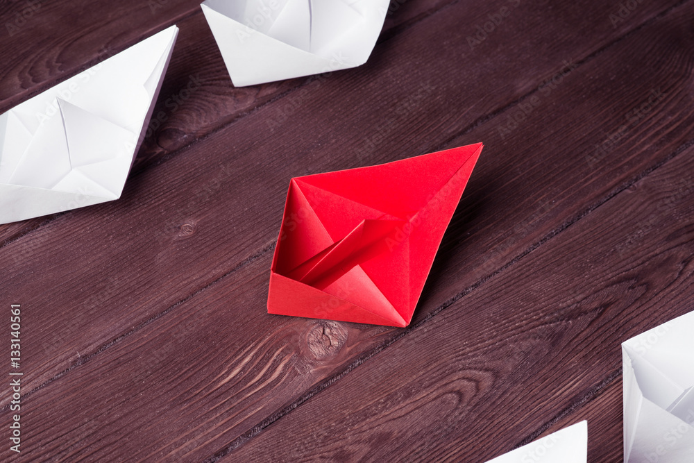 Business leadership concept with white and color paper boats on 