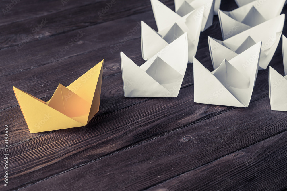 Business leadership concept with white and color paper boats on 