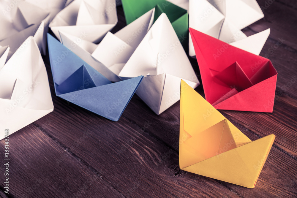 Business leadership concept with white and color paper boats on 