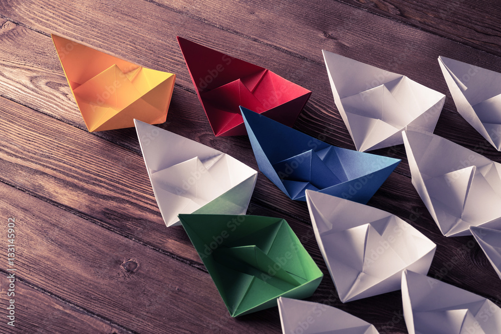 Business leadership concept with white and color paper boats on 