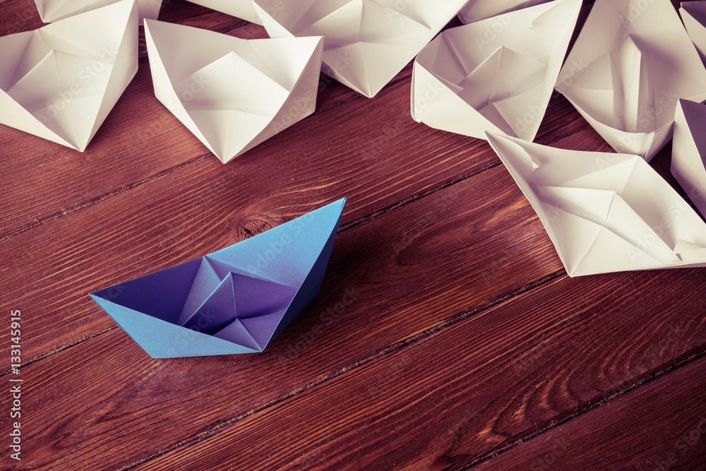 Business leadership concept with white and color paper boats on 