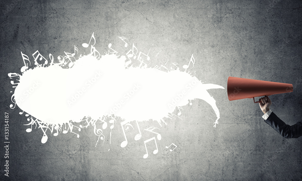 Hand of businesswoman holding red paper trumpet against concrete background