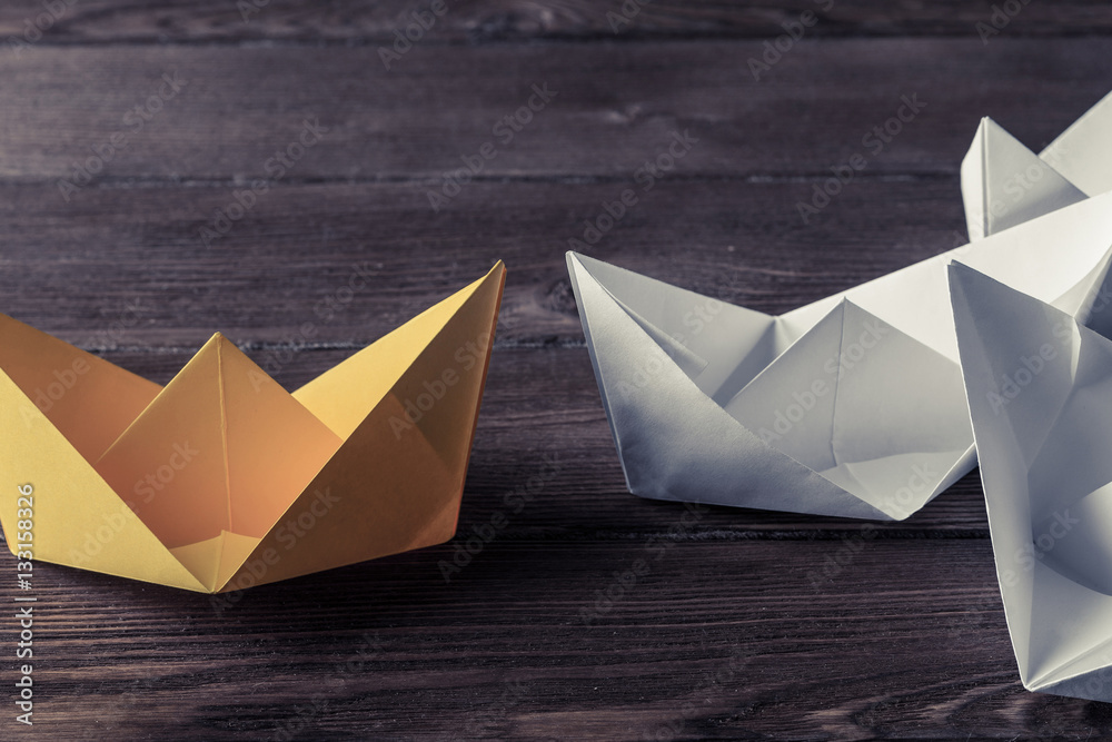 Business leadership concept with white and color paper boats on 