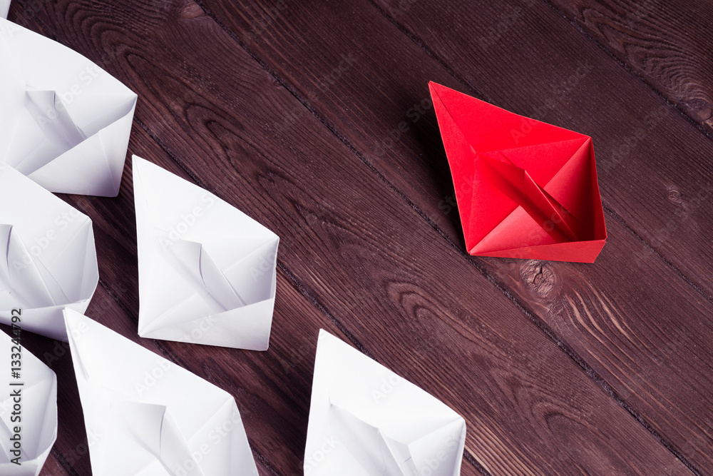 Business leadership concept with white and color paper boats on 