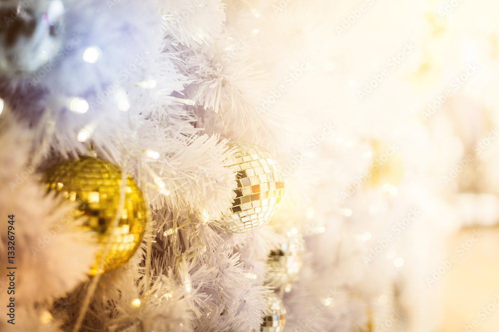 Closeup of red bauble hanging from a decorated Christmas tree. R