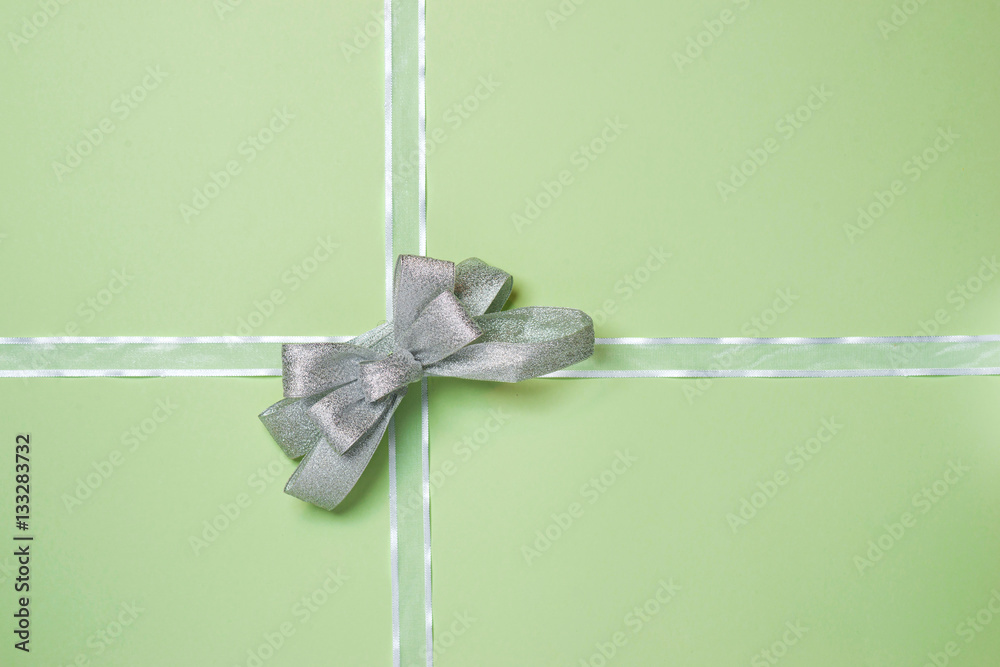 White ribbon with bow on green background.