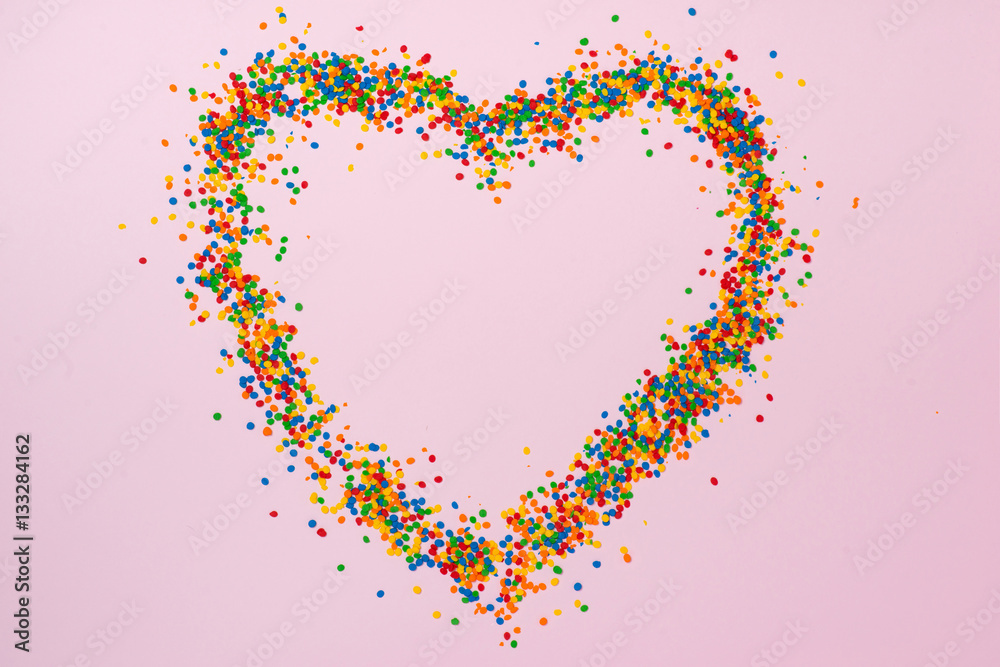 Valentines Day background. Heart shape with candies on pink.