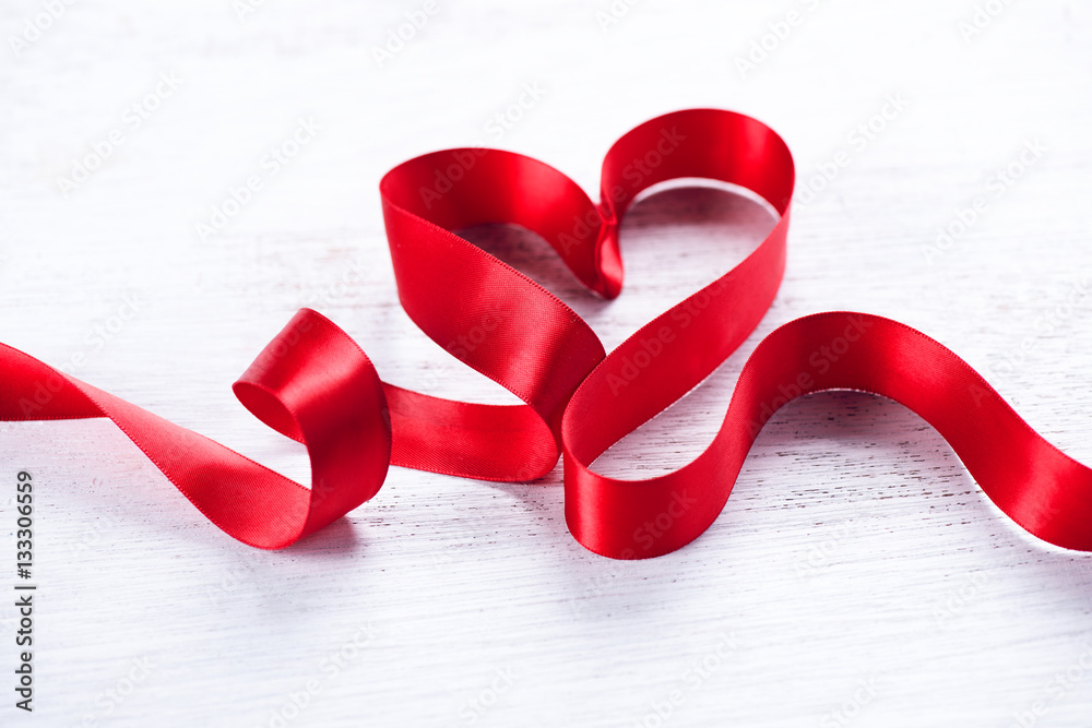 Valentines day background. Red heart shaped satin gift ribbon isolated on white