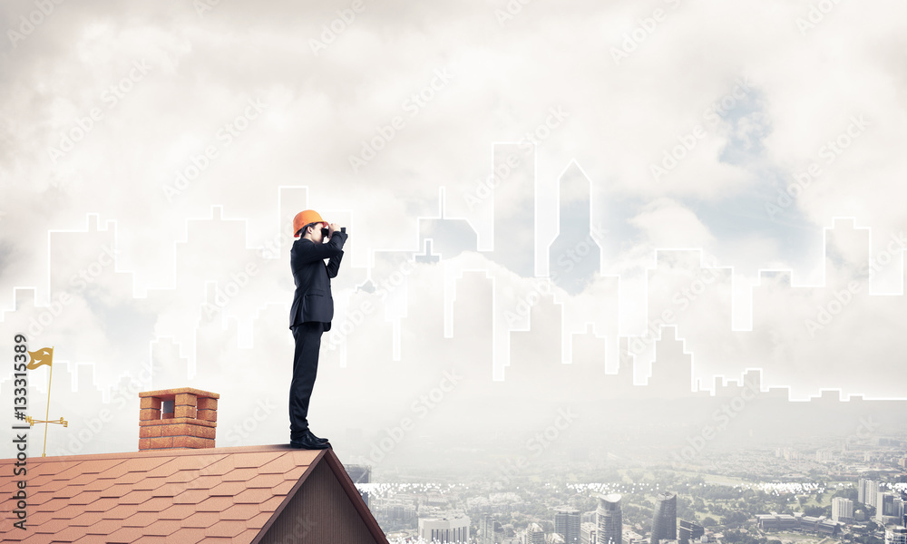 Engineer man standing on roof and looking in binoculars. Mixed m