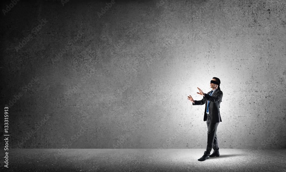 Business concept of risk with businessman wearing blindfold in empty concrete room