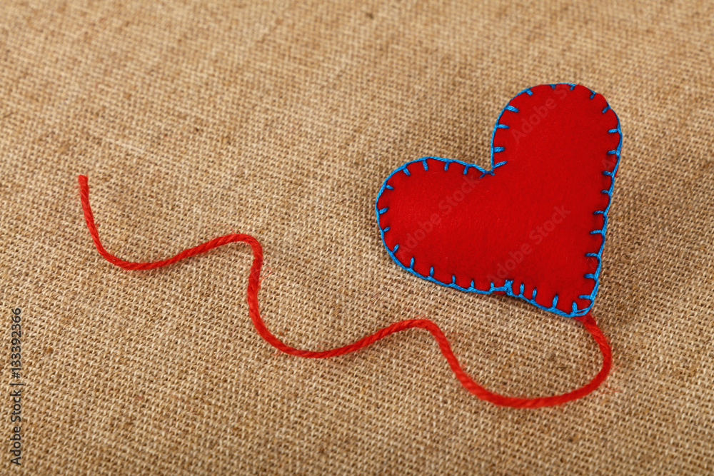 Red felt craft heart over canvas close up