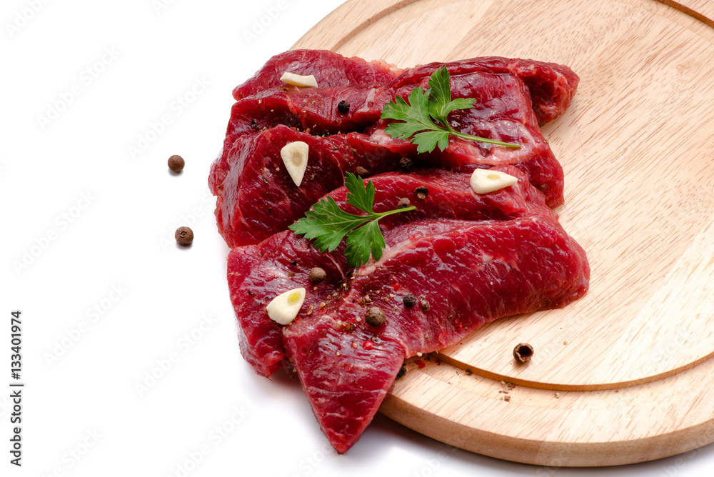 Pieces of meat with garlic and parsley on wooden board isolated. Raw beef. Top view.