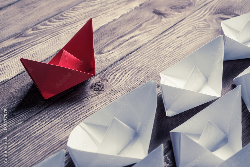 Business leadership concept with white and color paper boats on 