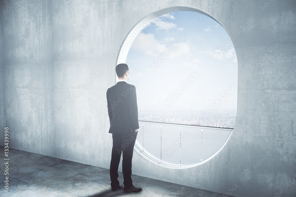 Thoughtful businessman in concrete interior side