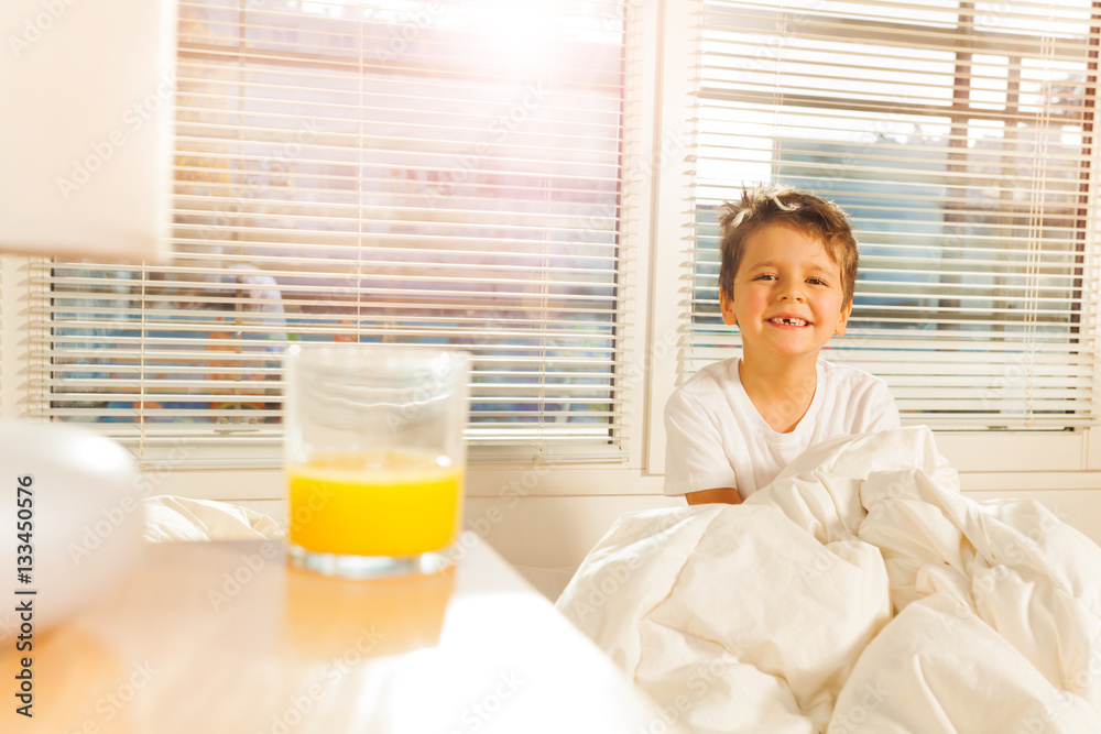 Happy boy starting his morning with glass of juice