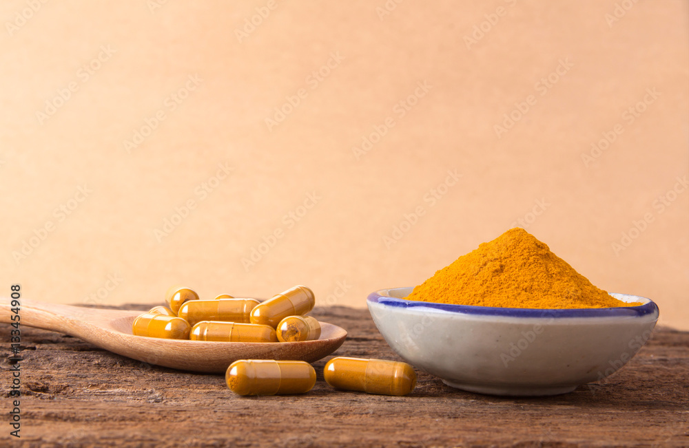 the turmeric powder , capsule and roots curcumin on wooden plate