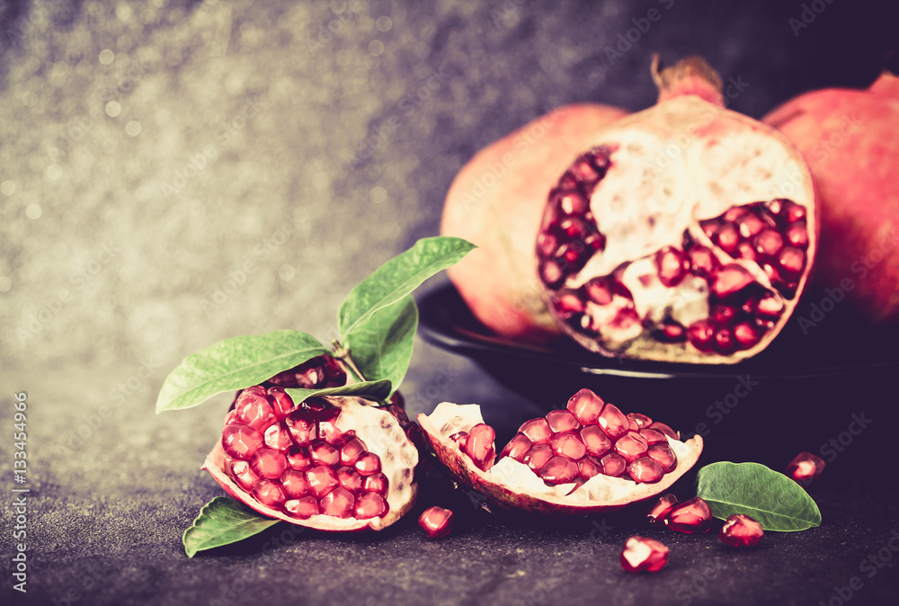 Fresh red pomegranate and seed  with leaves over black stone 