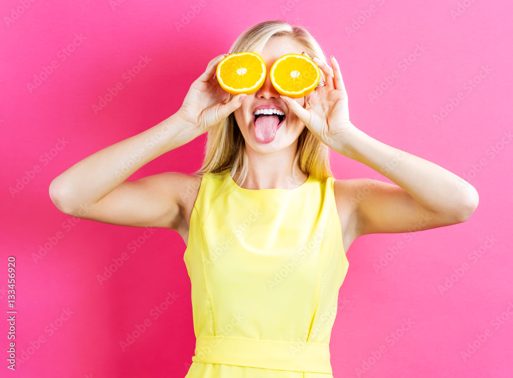 Happy young woman holding oranges halves