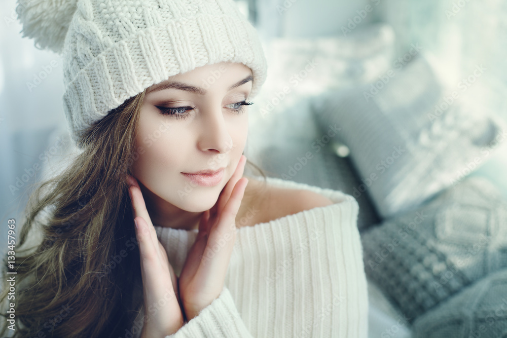 Indoor close up portrait of young beautiful girl touching her face, looking aside. Model wearing win